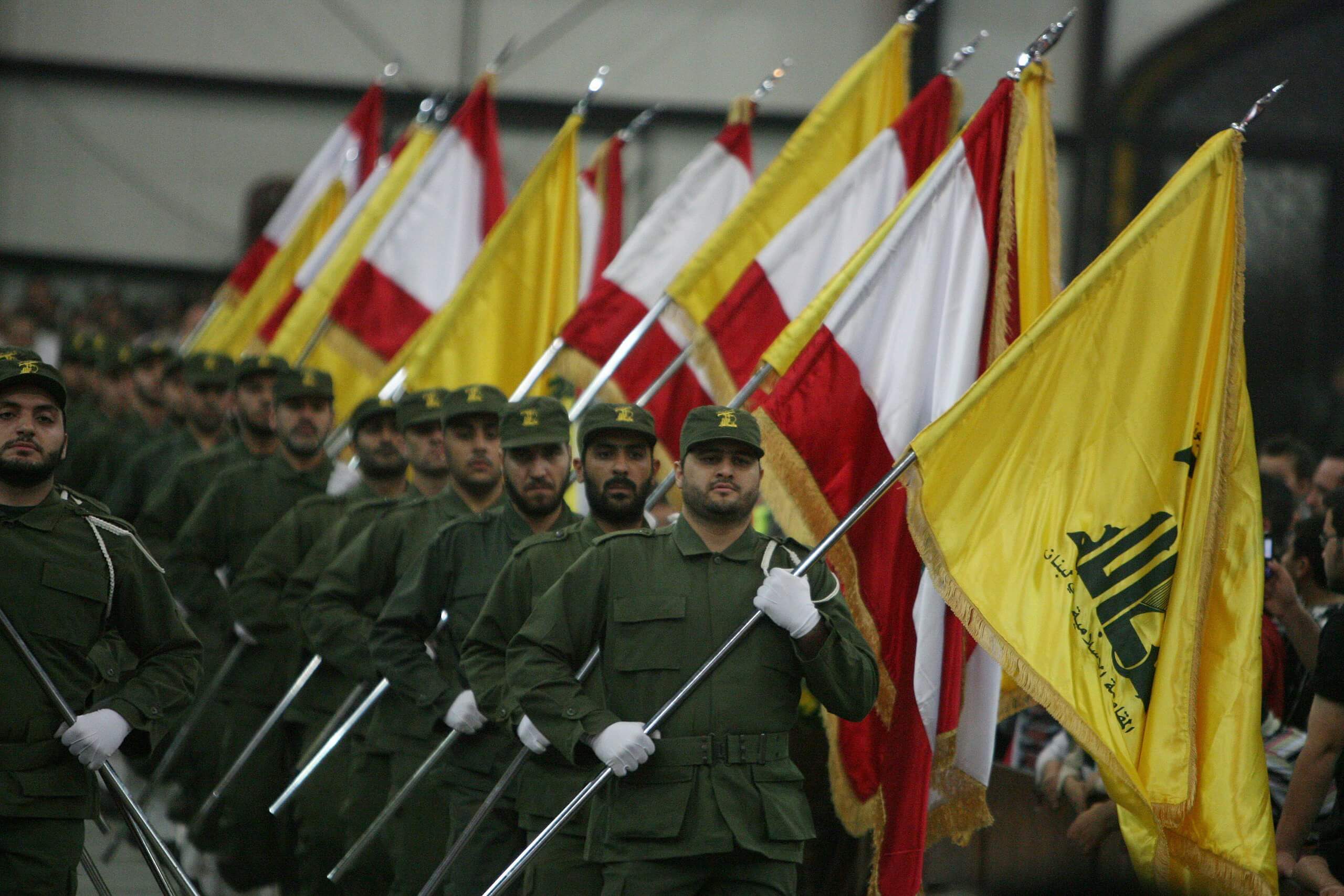 Miembros de Hezbolá sostienen banderas de la organización chií y Líbano durante una ceremonia.
