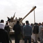 Rebeldes armados y curiosos civiles se reunieron en una de las principales puertas de entrada a la ciudad oriental de Ajdabiya para vitorear a los combatientes que se dirigían a los combates en 2011. Fuente: Al Jazeera.