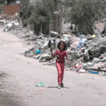 Una niña camina por el interior de Gaza durante el genocidio para conseguir alimentos