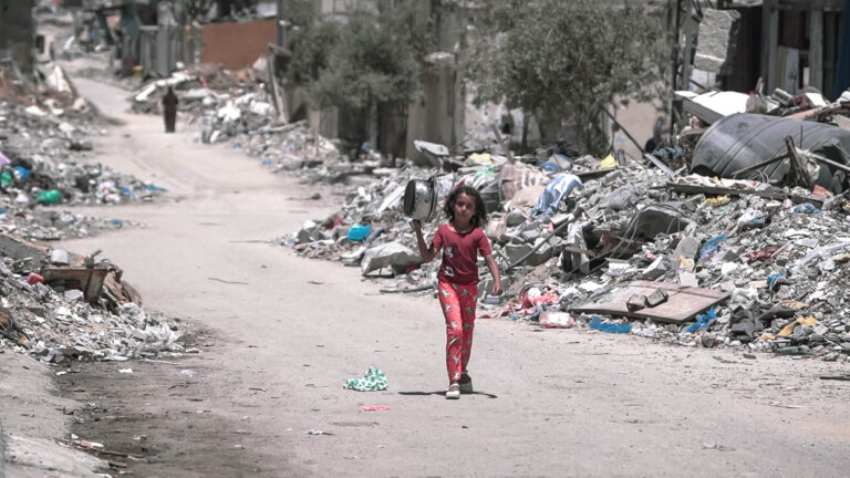 Una niña camina por el interior de Gaza durante el genocidio para conseguir alimentos